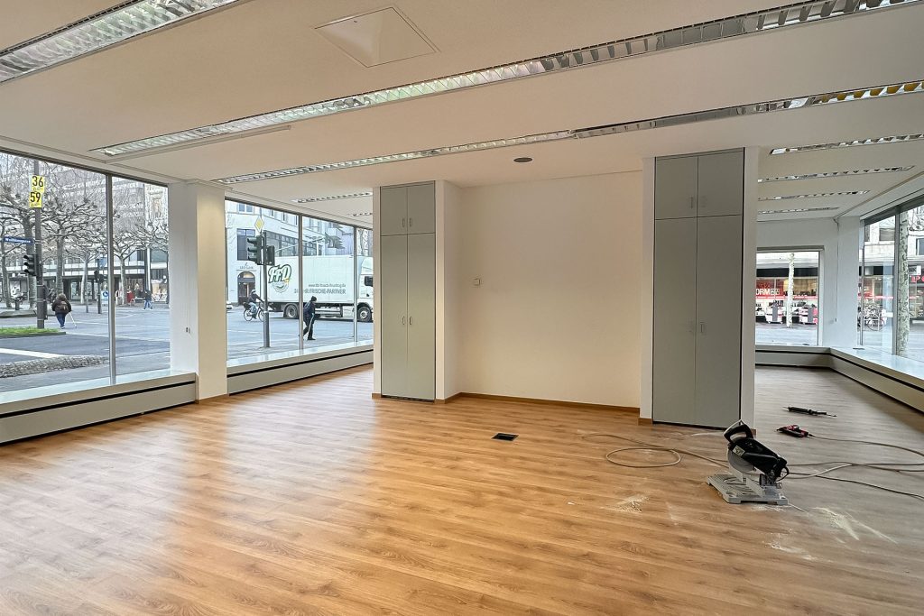 Leerer Molitor Pavillon mit Holzfußboden, großen Fenstern und zwei grauen Schränken an der Wand